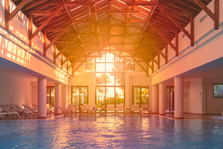 Empty Indoor pool at hotel. Nobody in water. Sunset sun shining in big window.のeditorial素材