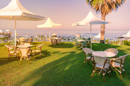 Beach in Turkey with green grass in foreground, white sun shade umbrellas sea and sunset sky in backgroundのeditorial素材