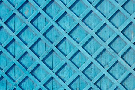 Wooden fence with pattern painted white. Blue colored planksの写真素材