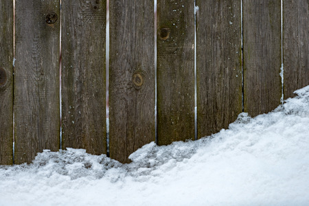 Wooden fence covered with white snow. Old plank background.の写真素材
