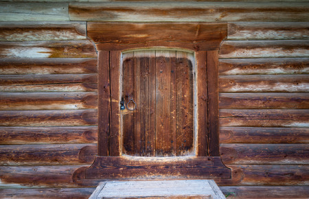 Old wood log background with cracks and lines. Door in the middle. Wall of house.の写真素材