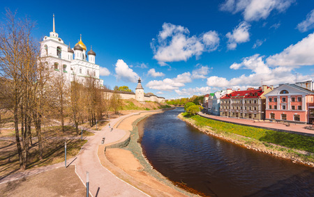 Pskov church and kremlin with blue cloudy sky in background. River in foreground. Church and houses on river sides.の写真素材