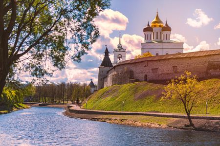 Pskov church and kremlin with blue cloudy sky in background. River in foreground.