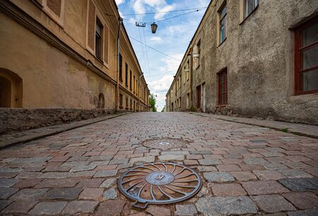 Old town street in Vyborg, Russia. Road with cobblestone floor. Blue cloudy sky in background.の写真素材