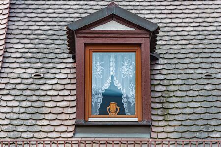 Dark old wooden window with beautiful vase. Tiled roof. Architecture and travel in Germany.の写真素材