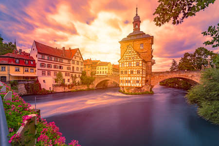 Bamberg city in Germany. Town hall building in background with blue cloudy sky.  Architecture and travel in Europe. Flowing river in foreground.のeditorial素材