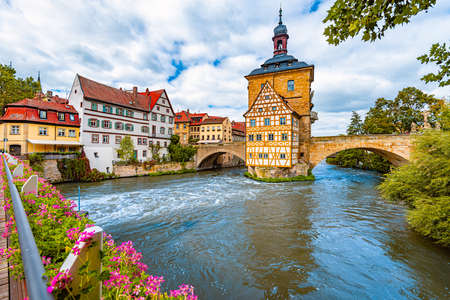 Bamberg city in Germany. Town hall building in background with blue cloudy sky.  Architecture and travel in Europe. Flowing river in foreground.のeditorial素材