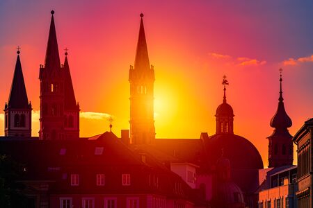 Sunset over city of Wurzburg in Bavaria, Germany. Beautiful sky with sun and clouds in background and old town architecture in foregroundの写真素材