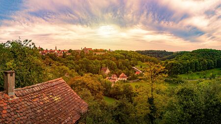 Panorama of Rothenburg Ob Der Tauber city in Bavaria, Germany, Europe. Old town on horizon, blue cloudy sky in background and tress in foregroundの写真素材