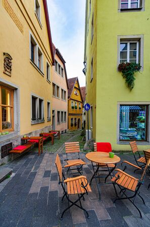 Table and chairs of street cafe in Rothenburg Ob Der Tauber, Bavaria, Germany, Europe. Old german architecture.の写真素材
