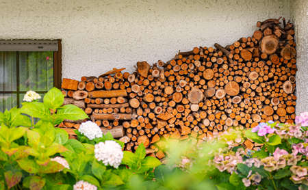 Stack of wood logs. Preparation of firewood for the winter. Pile of chopped lumber near house in Bavaria, Germany.の写真素材