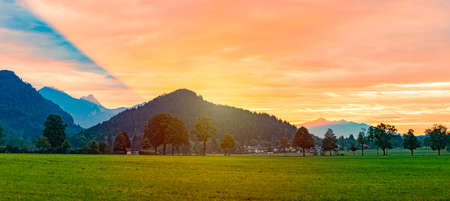 Mountains and lake in Bavaria, Germany, Europe. Sunrise scene with meadow in foreground and cloudy sky in backgroundの写真素材