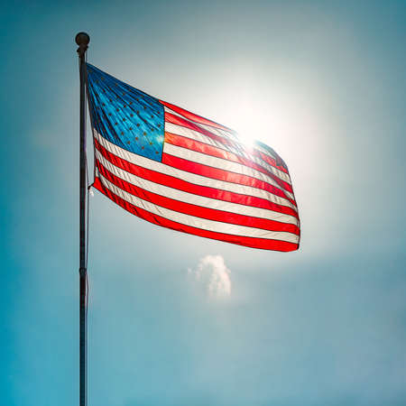 US american flag and blue cloudy sky with clouds in background