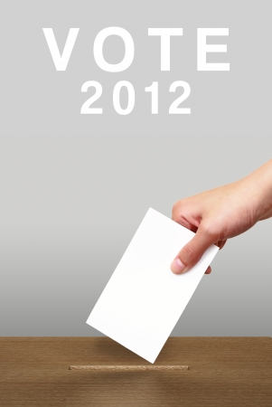 Hand putting a voting ballot in a slot of wooden box on white background, Vote 2012の写真素材