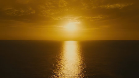 A golden-hued sunset illuminating the sky and ocean, creating a tranquil coastal ambiance.の素材