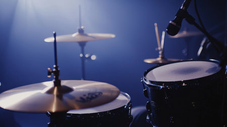 Close-up of a snare drum and cymbals under moody stage lighting, with atmospheric fog rolling in.の素材