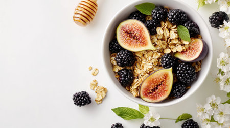 Granola bowl with figs, blackberries, and honey, captured from above on a white surface. The fresh ingredients create a visually appealing and nutritious meal.の素材