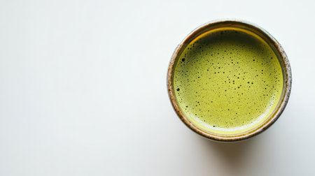 Top-down view of a vibrant matcha green tea cup on a white surface, highlighting the rich color and frothy texture of the beverage. Perfect for promoting health, wellness, or tea cultureの素材