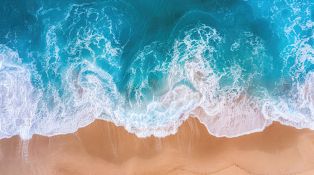 Aerial perspective of azure waves softly touching the sandy shore, evoking tranquility and beauty.の素材