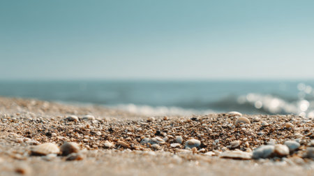 A serene close-up of sandy beach with delicate shells scattered across the shore, surrounded by gentle ocean waves and a radiant blue sky, perfect for relaxation.の素材