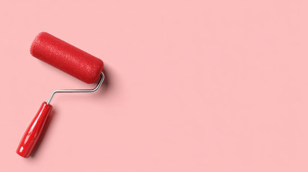 A vibrant red paint roller rests on a soft pastel pink background, illustrating tools for creative projects or home renovations. Perfect for design inspiration.の素材