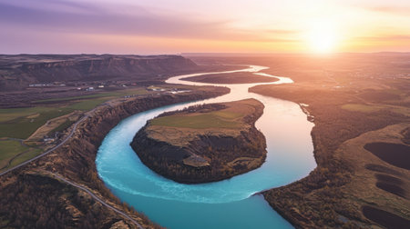 This breathtaking aerial view captures a meandering river flowing through lush green valleys, bathed in warm sunset light. Ideal for nature lovers and travelers.の素材