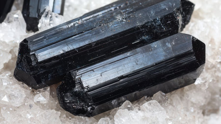 Shiny black tourmaline crystals resting in soft, diffused lighting, emphasizing their deep, earthy tones.の素材
