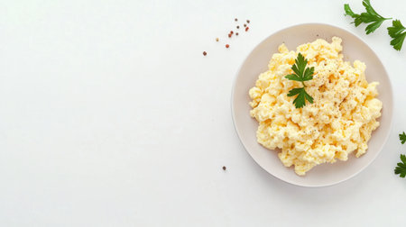 A plate of scrambled eggs with a sprig of parsley, isolated on a white background with ample copy space.の素材