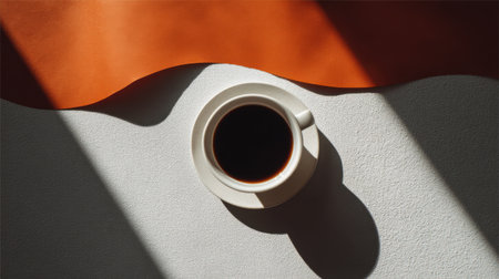 A stunning top view of a black coffee cup placed on a textured surface. The image captures warm shadows and vibrant colors, embodying minimalism.の素材