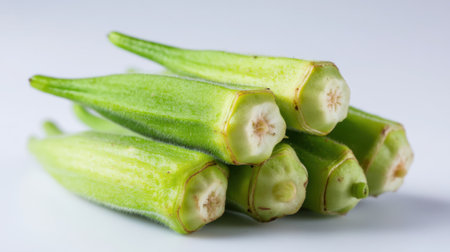 A vibrant display of fresh green okra stacked neatly on a plain background, highlighting its unique shape and glossy texture, ideal for healthy dishes.の素材