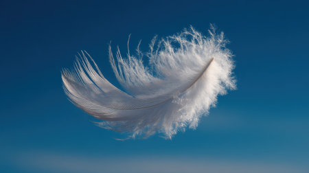 A stunning white feather is captured in mid-air against a vast blue sky, creating a serene and peaceful atmosphere, symbolizing purity and freedom.の素材