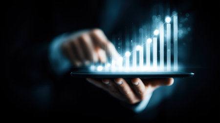 A person holds a tablet displaying a glowing graph that represents growth trends and data analytics, illustrating modern business insights.の素材