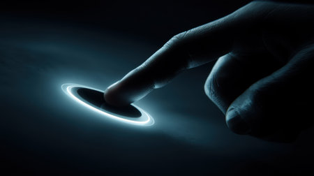 A close-up image of a finger gently touching a glowing circle of light against a dark backdrop, symbolizing technology, interaction, and innovation.の素材