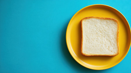 A freshly baked slice of white bread rests on a vibrant yellow plate, set against a bright blue background, perfect for food-related projects.の素材