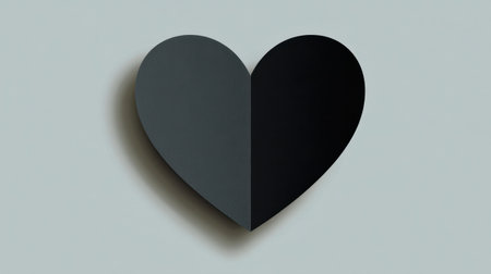 This artistic image features a heart shape divided into two contrasting shades of black and gray, set against a soft background. Perfect for themes of love and emotion.の素材