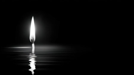 A solitary flame reflects beautifully on a still water surface, creating a serene and tranquil atmosphere. The black and white tones enhance the elegance and simplicity, making it perfect for moments of reflection or meditation.の素材