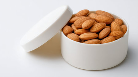This image features fresh almonds beautifully displayed in a white container, perfect for promoting healthy snacks and nutrition. Ideal for culinary and wellness uses.の素材