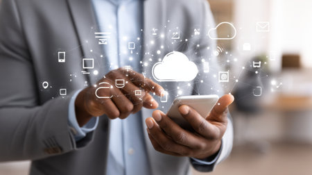 A businessman interacts with a smartphone, surrounded by cloud technology icons and digital symbols showcasing modern connectivity and innovation.の素材