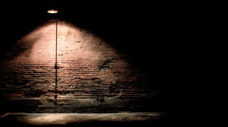 A captivating image of a shadowed brick wall illuminated by a single spotlight, showcasing dramatic contrasts in an empty urban space.の素材