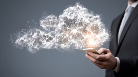 A businessman in a suit holds a smartphone, surrounded by a glowing cloud of data connections, illustrating modern digital innovation and technology trends.の素材