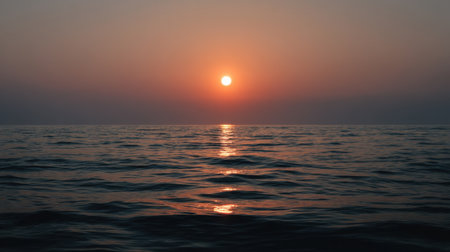 A breathtaking scene capturing a serene sunset over calm ocean waters, with warm tones illuminating gentle ripples and a peaceful horizon.の素材