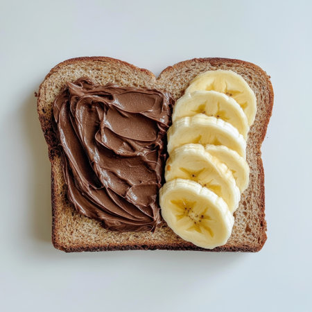 This enticing image features a slice of whole grain toast topped with rich chocolate spread and fresh banana slices. Ideal for breakfast ideas and snack inspiration.の素材