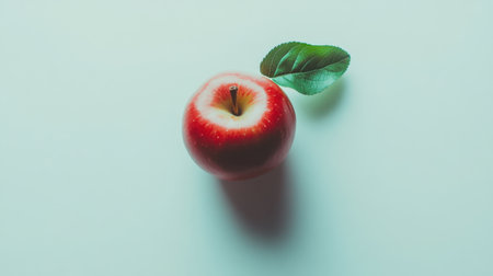 This stunning image features a fresh red apple paired with a vibrant green leaf, beautifully arranged on a soft background, symbolizing health and vitality.の素材