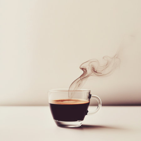 Capture the essence of morning with this beautiful shot of hot black coffee in a clear glass cup, steam rising gracefully against a soft background.の素材