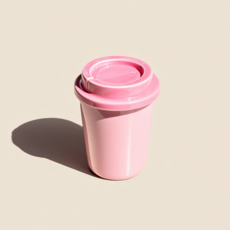 A charming pink coffee cup with a lid rests on a soft beige background. This image captures a minimalist and modern aesthetic perfect for lifestyle content.の素材