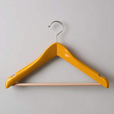 A bright yellow wooden hanger stands against a soft neutral background, highlighting its smooth design. Ideal for stylish home organization and fashion displays.の素材