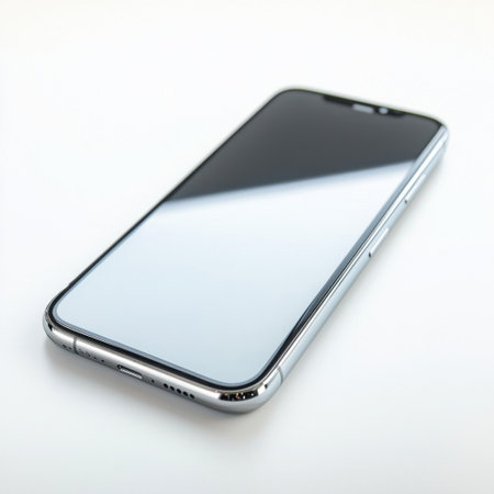A sleek modern smartphone lies on a white surface, showcasing its reflective screen and minimalist design, perfect for technology and lifestyle imagery.の素材