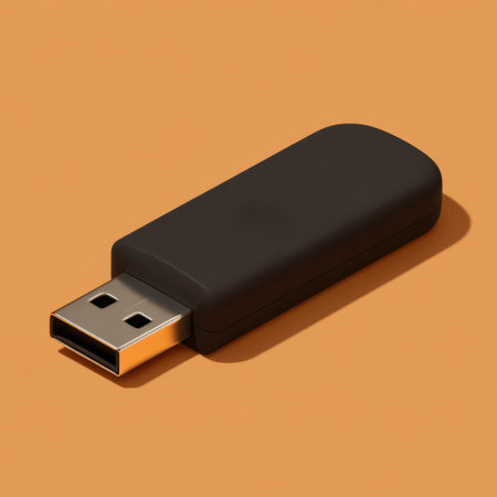 This image features a simple black USB drive placed on a warm orange background, perfect for highlighting technology and storage solutions.の素材