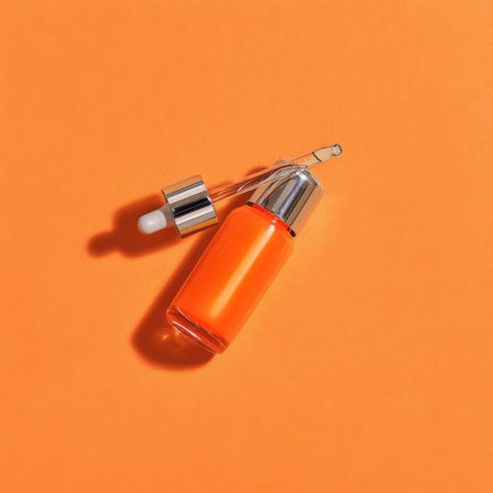 A striking bright orange serum bottle with a dropper sits on a vibrant orange background, perfect for skincare and beauty product displays.の素材