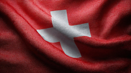 A close-up view of the Swiss flag, featuring rich red fabric with a striking white cross design. The textured material emphasizes national pride and identity.の素材